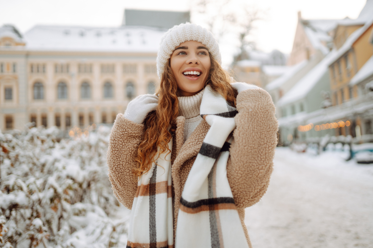 Happy woman having fun on a snowy street on a frosty morning in winter. A young woman walks through the city on a winter day. 