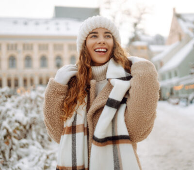 Happy woman having fun on a snowy street on a frosty morning in winter. A young woman walks through the city on a winter day.